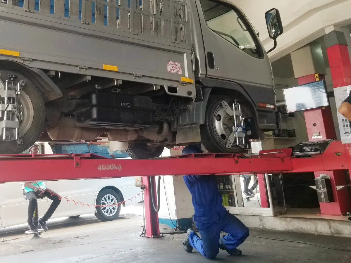 Interior da oficina Auto Suíça com um camião no elevador de alinhamento e um mecânico a trabalhar